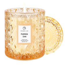 a candle that is next to a plate on a white surface with the label pumpkin chai