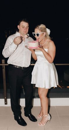 a man and woman standing next to each other with a cake in front of them