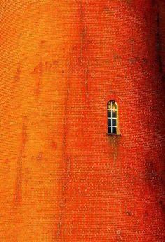 an orange brick wall with a window in it