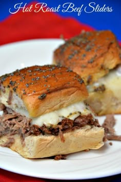 two sandwiches with meat and cheese are on a plate next to a red table cloth