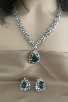 Elevate your style with our Emerald Green Silver Diamond Necklace Set, featuring high-quality CZ diamonds and matching studs. This exquisite set is perfect for engagement parties, cocktail events, and weddings, adding a touch of elegance to any occasion. The rich emerald green stones complement the sparkling silver diamonds, creating a captivating ensemble that matches effortlessly with your wardrobe. Embrace sophistication and glamour with this stunning jewelry set, designed to enhance your special moments.  All our products are crafted using traditional skills from our rich heritage. The manual nature of these crafts means that irregularities or variations may inherent in the handcrafting process. Luxury Heavy Traditional Emerald Necklace, Luxury Green Bridal Necklace With Cutdana, Green Luxury Temple Necklace For Formal Events, Luxury Green Diamond Bridal Necklace, Party Bridal Necklace With Stone Work And American Diamond, Party Bridal Necklace With American Diamond And Stone Work, Dazzling Bridal Necklace With Stone Work For Party, Party Bridal Necklace With Stone Work And Crystal, Crystal Bridal Necklace With Stone Work For Party