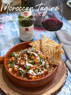 a bowl filled with food next to a bottle of wine