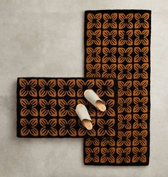 two pairs of white shoes sitting on top of a brown and black mat next to each other