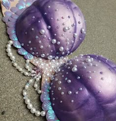 two purple balls with pearls on them are sitting next to each other in the sand