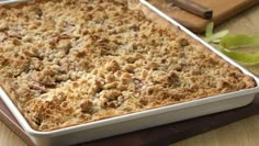 a casserole dish is sitting on a wooden table next to a cutting board