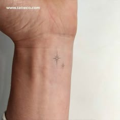 a small star tattoo on the wrist is shown in black and white ink, with an arrow