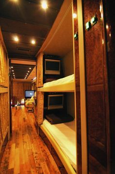 bunk beds are lined up in a room with wood flooring and lights on the ceiling