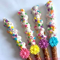 five decorated donuts with sprinkles and flowers on them are lined up in a row