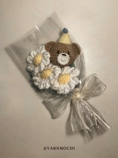 a teddy bear in a crochet hat with white and yellow flowers on it