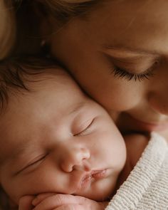 a close up of a person holding a baby with their face next to her head