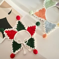 three crocheted christmas decorations are on the table next to a card and scissors