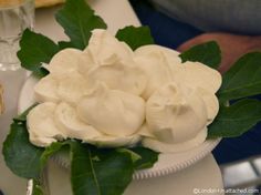 a white plate topped with whipped cream surrounded by leaves