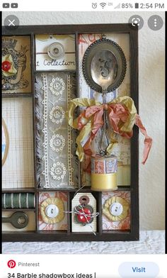 an assortment of decorative items is displayed in a shadow box with ribbon and spoons