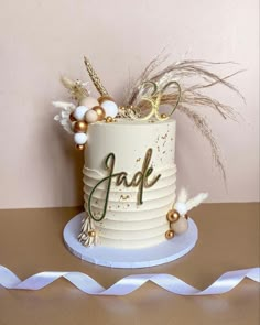 a white cake with gold letters and feathers on top