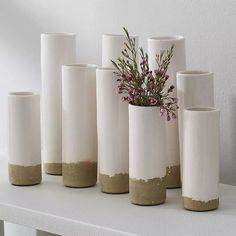 several white vases with flowers in them on a table