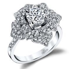 a white gold ring with an intricate flower design and round diamonds on the band, set in