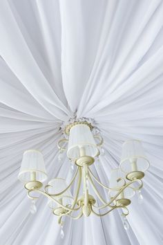 a chandelier hanging from the ceiling with white drapes