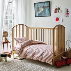 a small child's bed in the corner of a room with pictures on the wall