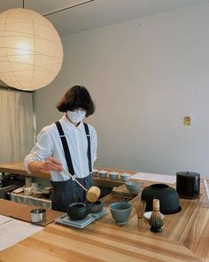 a person wearing a white shirt and black suspenders preparing food on a wooden table