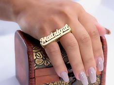 a close up of a person's hand with a ring on top of a purse