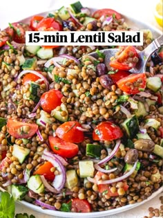 a white bowl filled with lentil salad and topped with tomatoes, cucumbers, red onion, lettuce