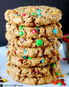 a stack of cookies with m & m candies on top and a bowl of candy in the background