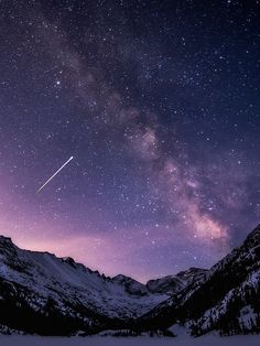 the night sky is filled with stars, and there are mountains in the foreground