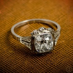 an old - fashioned diamond ring sits on top of a brown cloth with diamonds around it