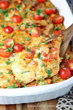 a casserole dish with tomatoes, cheese and parsley on the top is being scooped out