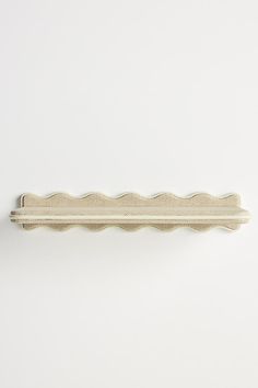 a white wall mounted shelf with scalloped edges