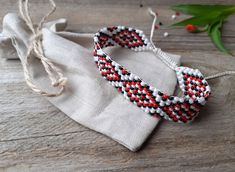 two bracelets sitting on top of a white cloth bag next to some flowers and twine