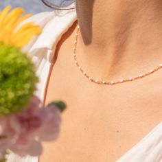 a close up of a woman wearing a necklace with flowers in front of her chest