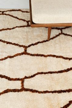 a white rug with brown lines on it and a wooden bench in the corner next to it