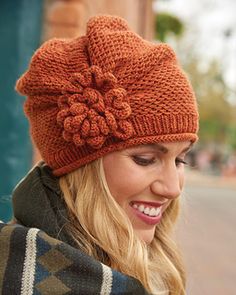 a woman wearing an orange knitted hat with a flower on the front and side