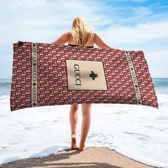 a woman is walking on the beach holding a towel