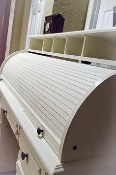 a white bench sitting in front of a mirror next to a door with drawers on it