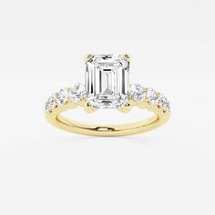 an emerald cut diamond engagement ring with two side stones on the band, set in yellow gold