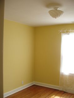 an empty room with yellow walls and wood floors