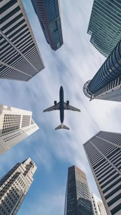 an airplane is flying through the sky between tall buildings