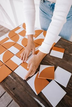 a person cutting out pieces of paper with scissors on a wooden table in front of them