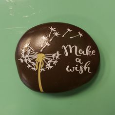 a painted rock with the words make a wish written on it and dandelions