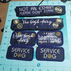 four patches with words on them sitting on a cutting board next to scissors and thread