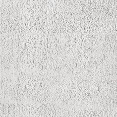 a white textured wall with some black dots on it