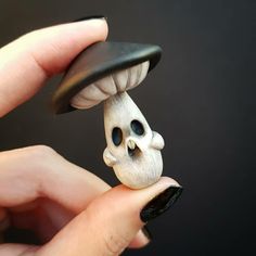 a hand holding a tiny figurine with a mushroom on it's head