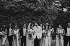 a group of people standing next to each other in front of some trees and bushes