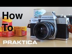 an old camera sitting on top of a wooden table next to some boxes and cups