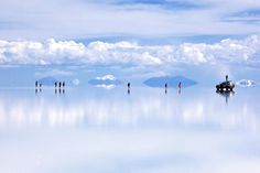 a group of people standing on top of a large body of water with mountains in the background