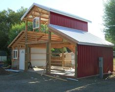 a red barn with a metal roof next to trees