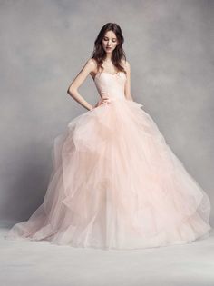 a woman in a pink wedding dress posing for a photo with her hands on her hips