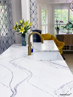 a kitchen with marble counter tops and yellow chairs